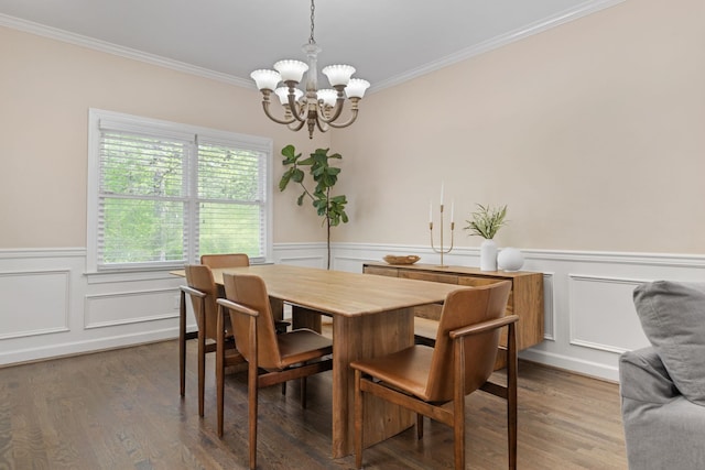 dining area featuring wainscoting, ornamental molding, a chandelier, wood finished floors, and a decorative wall