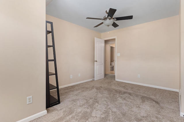 carpeted empty room with a ceiling fan and baseboards