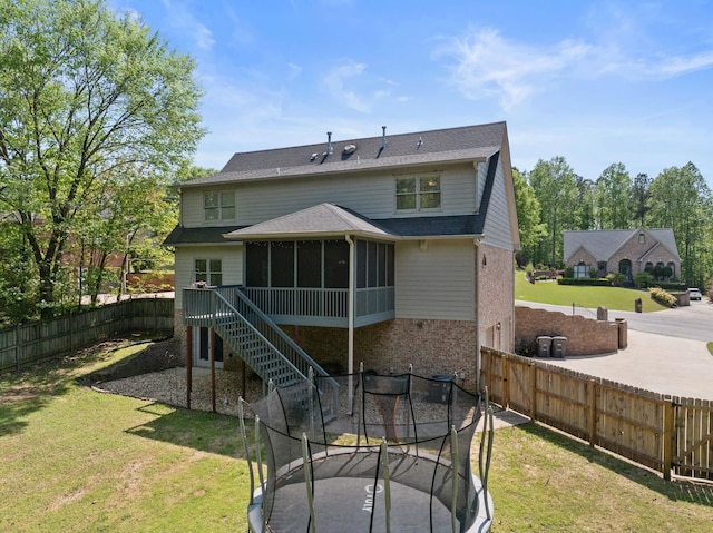 rear view of property with a sunroom, a trampoline, and stairway