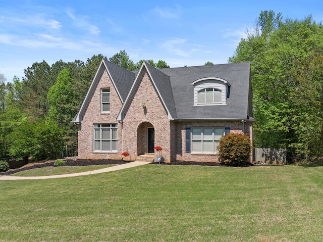 view of front of house featuring brick siding, a front lawn, and roof with shingles
