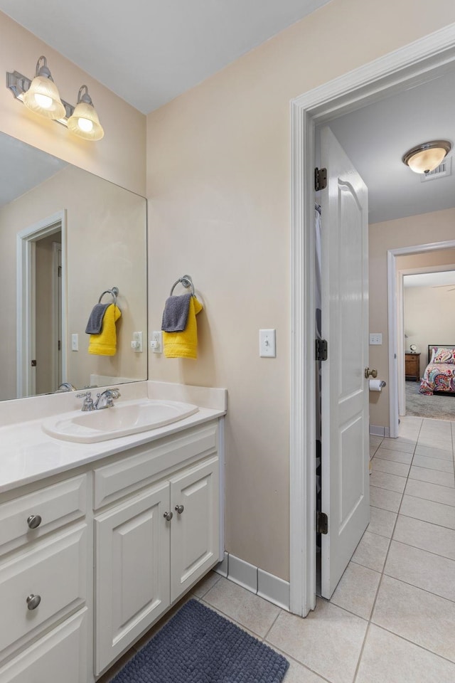 bathroom featuring tile patterned floors, vanity, baseboards, and ensuite bathroom