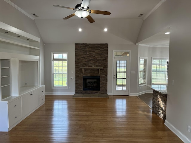  - unfurnished living room featuring lofted ceiling, wood finished floors, a ceiling fan, a fireplace, and crown molding