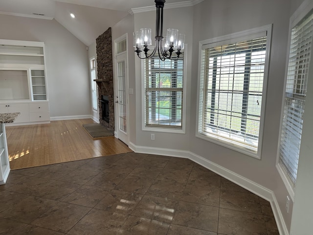  - unfurnished dining area with a chandelier, a stone fireplace, vaulted ceiling, built in features, and dark tile patterned floors