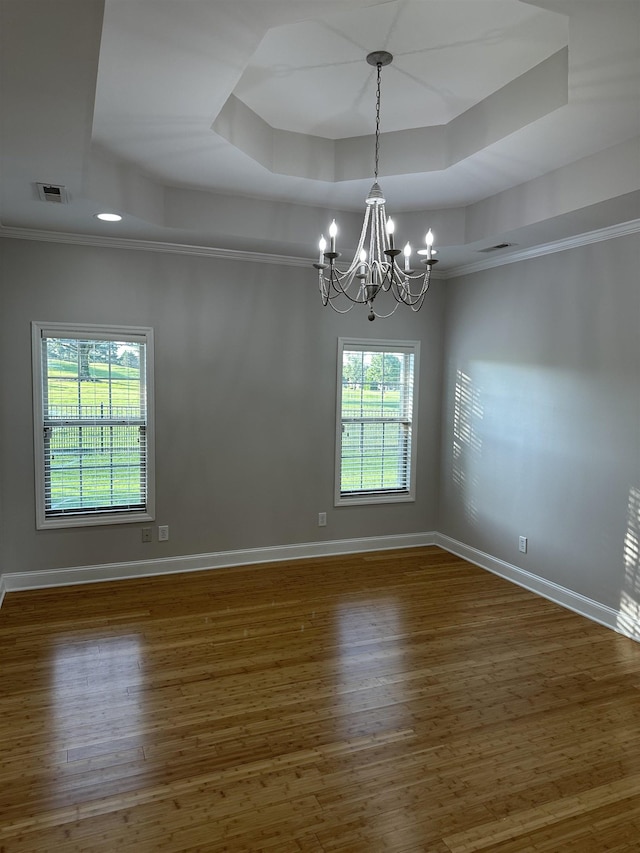  - unfurnished room with a raised ceiling, a chandelier, wood finished floors, and crown molding