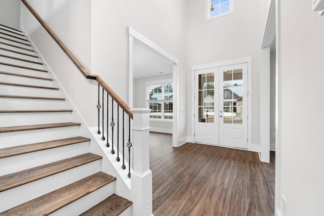 foyer entrance with french doors, a towering ceiling, and dark wood-type flooring