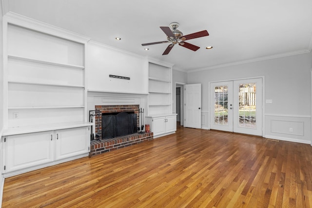 unfurnished living room featuring crown molding, a brick fireplace, ceiling fan, and french doors