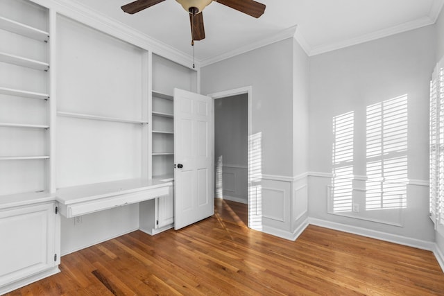 interior space with crown molding, ceiling fan, wood-type flooring, and built in desk