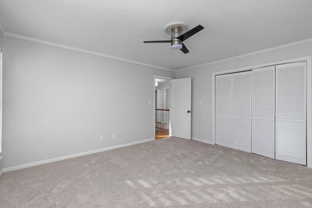 unfurnished bedroom featuring crown molding, light carpet, ceiling fan, and a closet