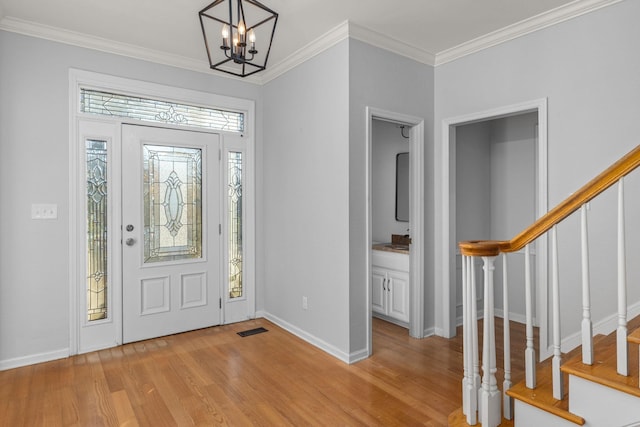 foyer featuring ornamental molding, light wood-type flooring, and a notable chandelier