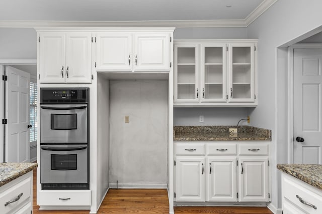 kitchen featuring stainless steel double oven, white cabinets, and dark stone counters