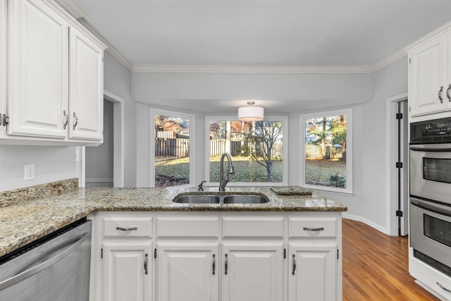 kitchen with sink, light stone countertops, white cabinets, and appliances with stainless steel finishes