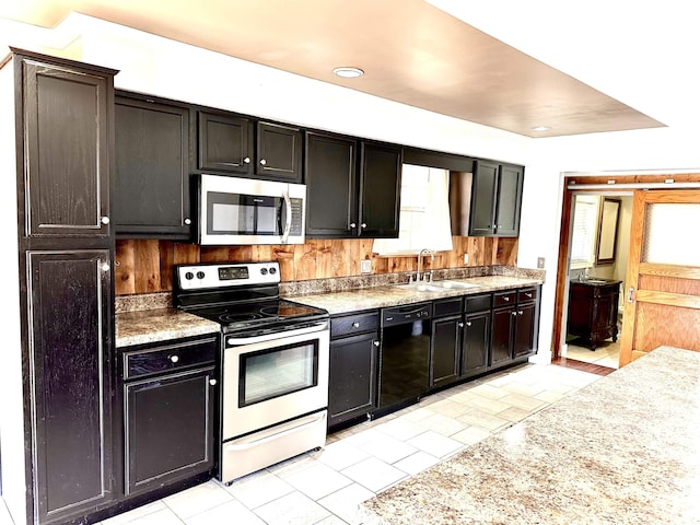 kitchen with light stone counters, sink, stainless steel appliances, and a healthy amount of sunlight