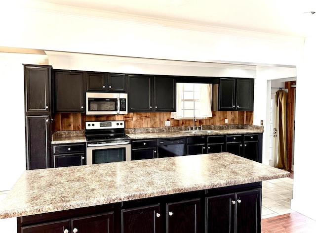 kitchen featuring stainless steel appliances, crown molding, a kitchen island, and sink