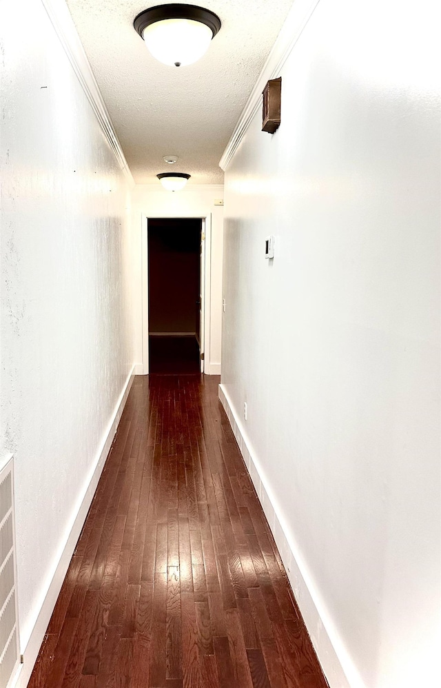 hallway with crown molding, dark hardwood / wood-style floors, and a textured ceiling