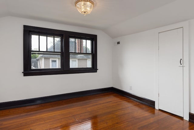 - unfurnished bedroom with hardwood / wood-style flooring, visible vents, and lofted ceiling