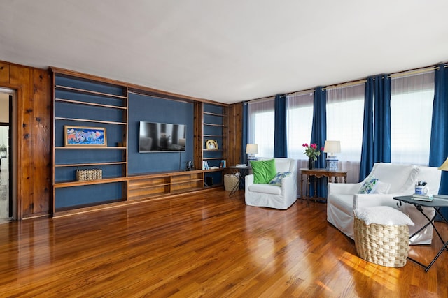  - living area with built in features, wood finished floors, and wooden walls