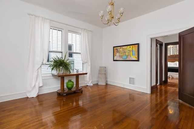  - interior space featuring baseboards, a chandelier, hardwood / wood-style floors, and visible vents