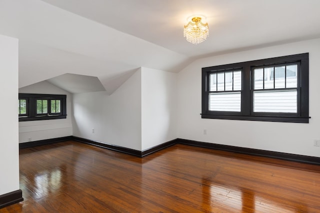  - bonus room with baseboards, a notable chandelier, hardwood / wood-style flooring, and lofted ceiling