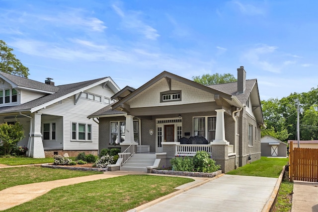  - view of front of property with brick siding, a front lawn, covered porch, and a chimney