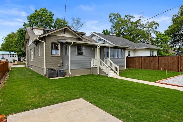  - rear view of house with brick siding, fence, a yard, and cooling unit