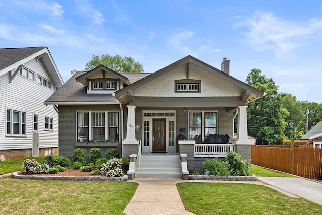 - craftsman inspired home featuring a chimney, a porch, a front lawn, and brick siding