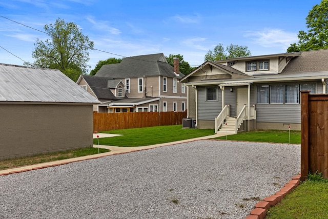  - exterior space featuring fence, central AC unit, entry steps, and a front lawn