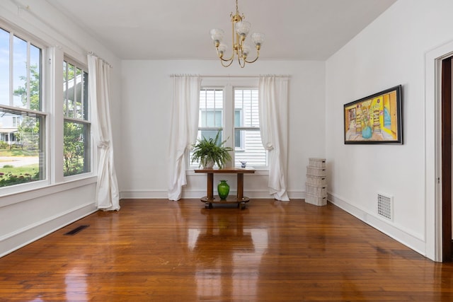  - unfurnished dining area with visible vents, baseboards, wood finished floors, and an inviting chandelier