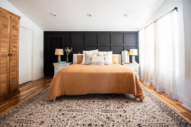 bedroom featuring light hardwood / wood-style floors, vaulted ceiling, and multiple windows