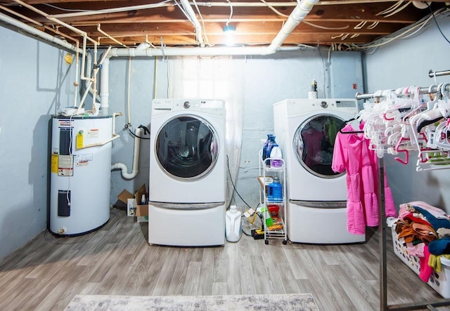 laundry room featuring washer and dryer, wood-type flooring, and electric water heater