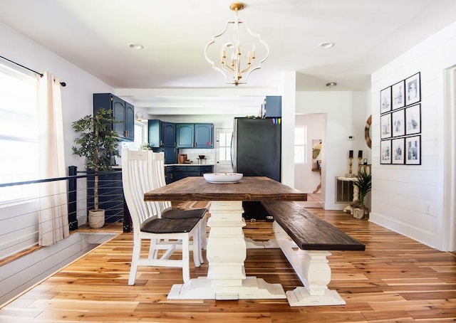 dining area with a notable chandelier, plenty of natural light, and light wood-type flooring