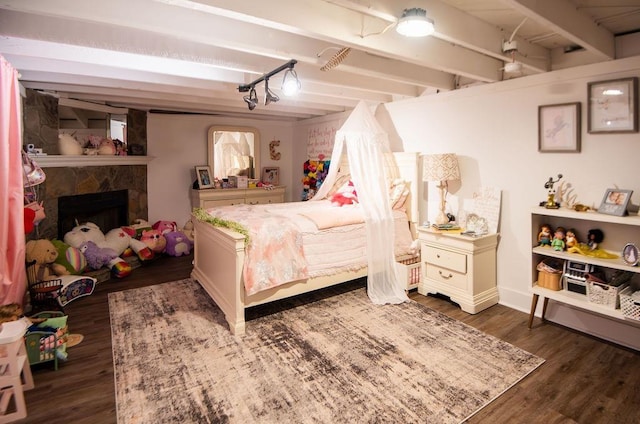 bedroom with beamed ceiling, a stone fireplace, and dark hardwood / wood-style flooring