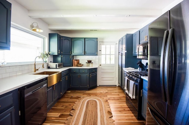 kitchen featuring backsplash, black appliances, sink, plenty of natural light, and beam ceiling