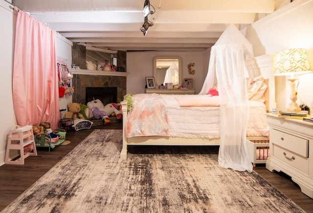 bedroom with beam ceiling, dark hardwood / wood-style floors, and a tiled fireplace