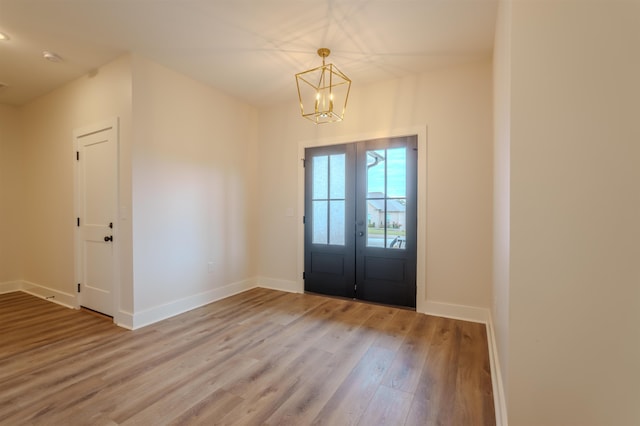 foyer with a chandelier, french doors, wood finished floors, and baseboards