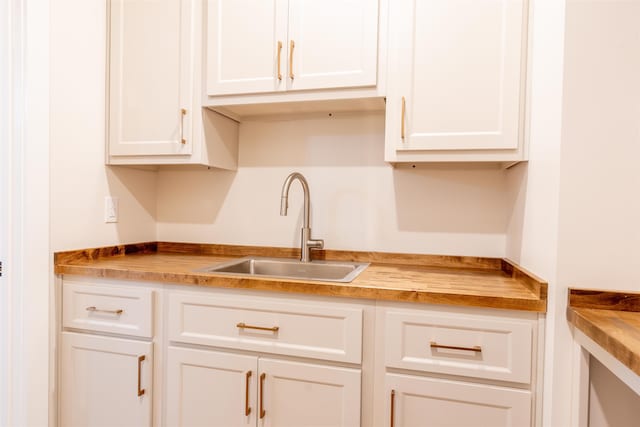 kitchen featuring white cabinetry, a sink, and wood counters