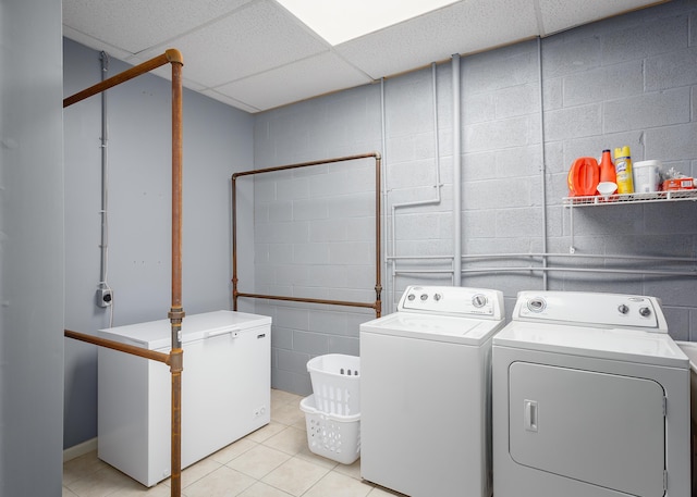 laundry room featuring light tile patterned floors, washer and clothes dryer, and concrete block wall