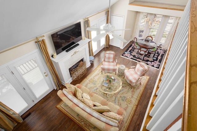 living room featuring dark wood-style floors, a brick fireplace, vaulted ceiling, and a ceiling fan