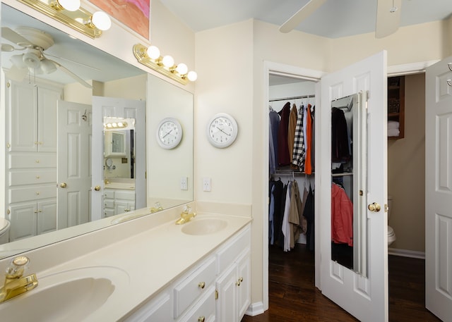 bathroom featuring double vanity, wood finished floors, a sink, and toilet