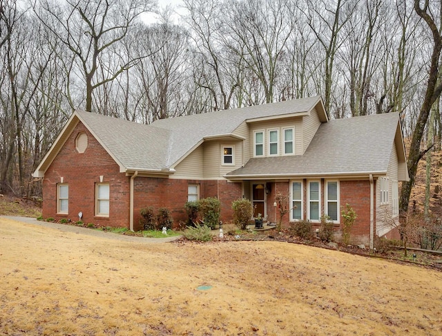 view of front of property featuring brick siding and roof with shingles