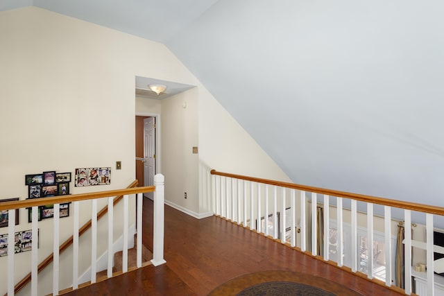 corridor with lofted ceiling, wood finished floors, an upstairs landing, and baseboards