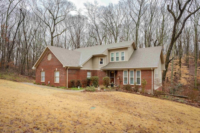 view of front of property with a shingled roof and brick siding