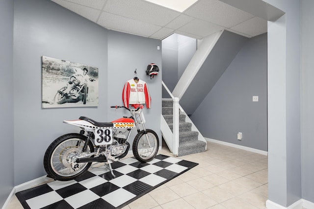 interior space featuring a paneled ceiling, baseboards, and tile patterned floors