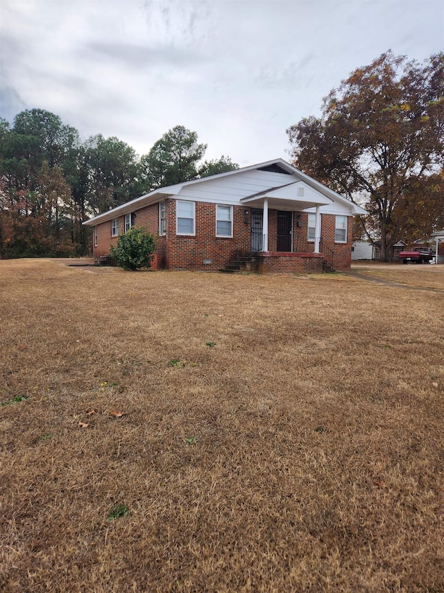 ranch-style home featuring covered porch and a front lawn