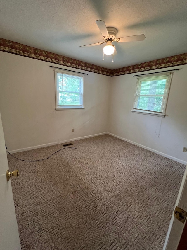 spare room featuring carpet, visible vents, ceiling fan, and plenty of natural light