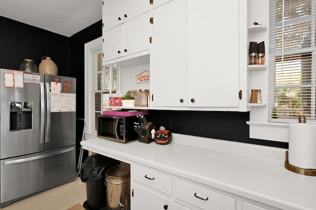 kitchen featuring stainless steel fridge with ice dispenser and white cabinetry