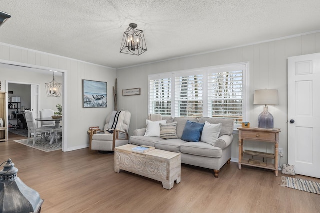 living room featuring ornamental molding, wood-type flooring, and a chandelier