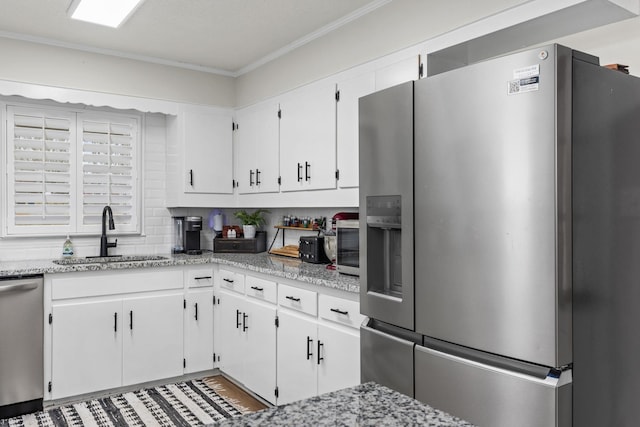 kitchen with stainless steel appliances, light stone countertops, sink, and white cabinets