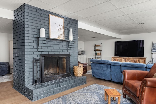 living room featuring a fireplace, hardwood / wood-style floors, and a drop ceiling