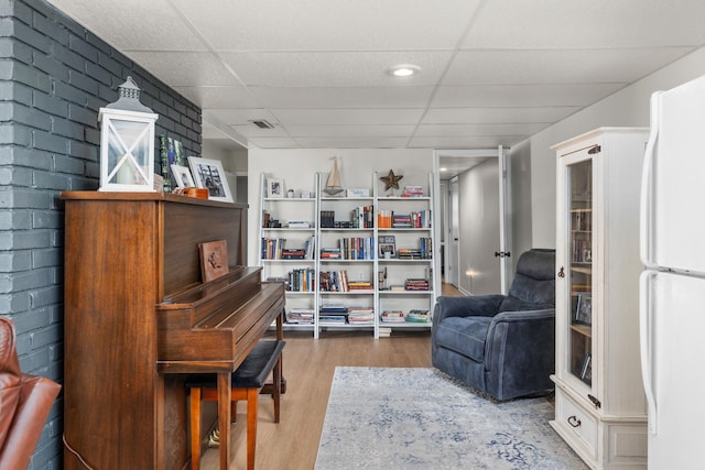 sitting room featuring hardwood / wood-style floors and a drop ceiling