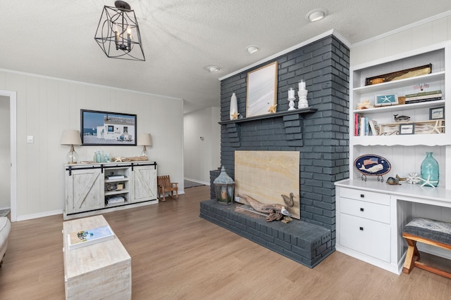 living room featuring crown molding, a textured ceiling, light wood-type flooring, built in features, and a fireplace